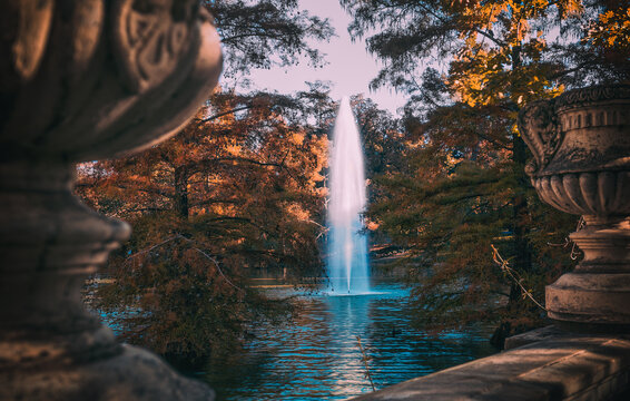 Jard&iacute;n para relajarse en oto&ntilde;o junto a un lago , fuente de agua en medio del parque, chorro de agua en vertical saliendo del lago en oto&ntilde;o, lugar de relajaci&oacute;n y de encuentro de paz  en el parque