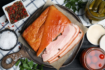 Flat lay composition with delicious smoked bacon on black wooden table