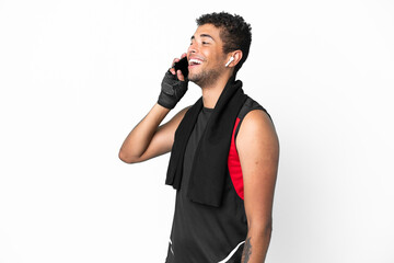 Sport brazilian man with towel isolated on white background keeping a conversation with the mobile phone