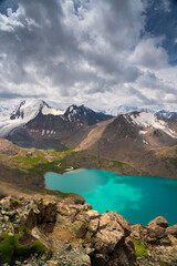 Naklejka na ściany i meble A beautiful alpine lake Ala-Kul in Kyrgyzstan, panoramic view from a height of 3900 m above sea level. A wonderful combination of nature, turquoise water, snowy mountains and clouds.