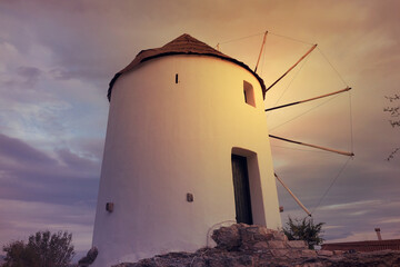 Beautiful dramatic sunset over windmill as seen in island of Santorini, Cyclades, Greece