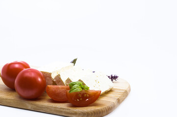 close up Feta cheese, ripe tomatoes, tomato slices, basil on a wooden board, vegetarian, lifestyle, life concept	