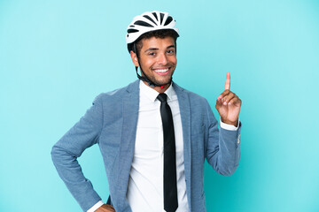Young business Brazilian man with bike helmet isolated on blue background showing and lifting a finger in sign of the best