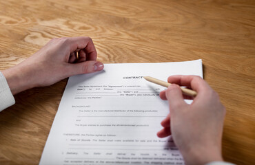 Paper sales contract on office desk in hands with pen, pov.