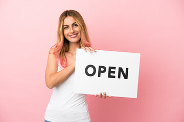 Young woman over isolated pink background holding a placard with peace symbol with happy expression