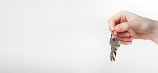 Hand holding keys on keyring over white background. Promo banner for real estate advertising with copy space for text.