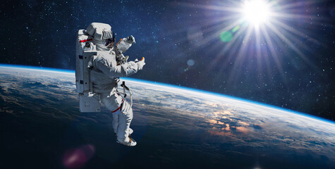 Astronaut in outer space on orbit of Earth planet. Sky and clouds. Spacewalk with stars. Sun light...