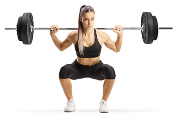 Full length portrait of a young female bodybuilder lifting weights and kneeling