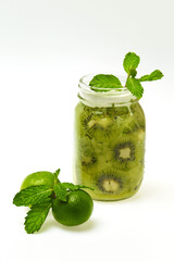 Jar of green kiwi smoothie decorated with mint an limes isolated at white background. Natural superfood. Healthy lifestyle.