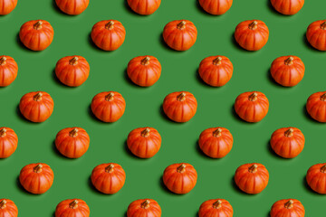 Orange decorative pumpkin on a green background with a shadow. Photo of isolated objects for design. Seamless pattern for Halloween. Horizontal photo.