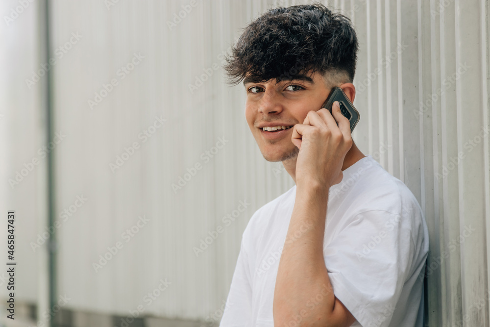 Wall mural portrait teenager boy talking on mobile phone on street wall