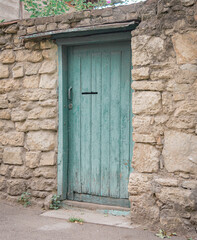 Fototapeta na wymiar Green door in the stone fence colored