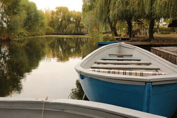Obraz premium Light blue wooden boat on lake, space for text