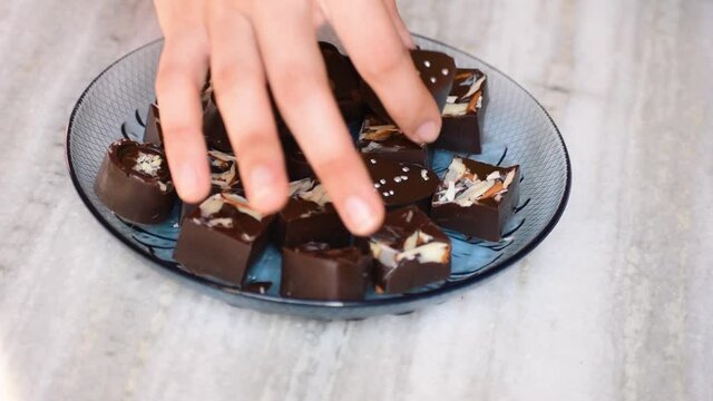 Close up shot of female hand putting handmade chocolates in plate. Sweets in Diwali festival. Holiday gift concept