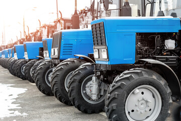 Many different tractors standing in row at agricultural fair for sale outdoors.Equipment for...
