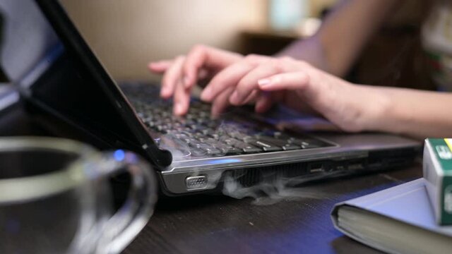 A close-up of an old laptop falling apart with smoke coming out of it. Short circuit and death of an old computer