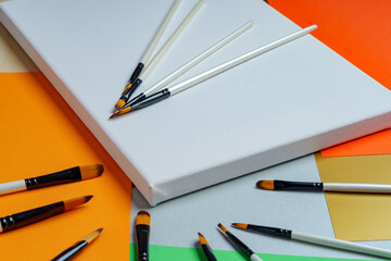 New brushes of various sizes lie on a new canvas and a paradise with it.