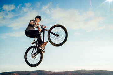 Fototapeta na wymiar Mountain biker flying through the air after jumping off a ramp