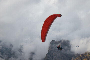 paragliding in the air, sports, parachute on the background of mountains, rocks, fog, clouds
