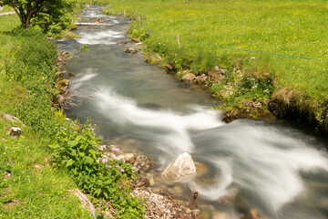Naklejka na ściany i meble Appenzell, Switzerland, June 13, 2021 Little alpine river flows through a green meadow