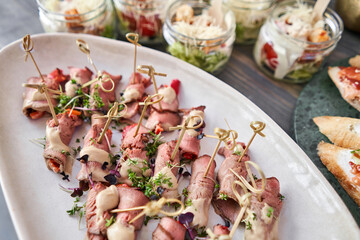 Delicious canapes with pork ham with dried tomatoes. Tasty buffet table. Summer party. Catering concept