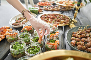 The waiter sets the table. Delicious fresh seafood, shrimp with fresh vegetables. buffet table with lots of delicious snacks.