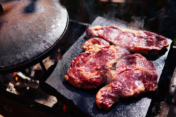 Raw beef burger steak on grill. Cutlet meat placed on grill stone with fire.