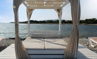 empty booths with blue curtains in the early morning against the background of the sea and the blue sky. the concept of a holiday at the sea
