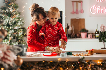 happy family mothe and daughter bake cookies for christmas in the kitchen with garlands