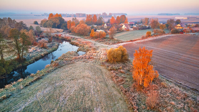 Autumn rural landscape. Frost on grass. River, field, meadow, village, fall color trees.
