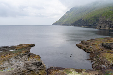 Beautiful aerial view of Faroe Islands Towns next to the ocean Canals, and boats and massive mountains. 