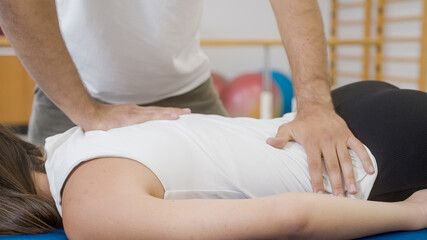 Physiotherapist's hands doing medical back massage, to a female patient, during a rehabilitation treatment.