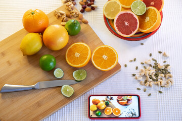 View from above of a mix of citrus fruits, whole or cut in half. Oranges, grapefruits, lemons and limes on a wooden cutting board