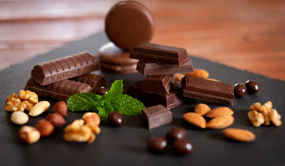 Pieces of dark chocolate and dried fruit on black background. Wooden table and back lit