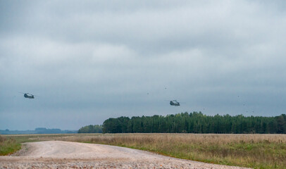 Two British Army Boeing CH-47 Chinook helicopters flying low in a cloudy blue grey and white winter sky on a military exercise, Wiltshire UK