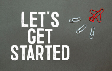 Let's get started word on white ring binder notebook with hand holding pencil on wood...