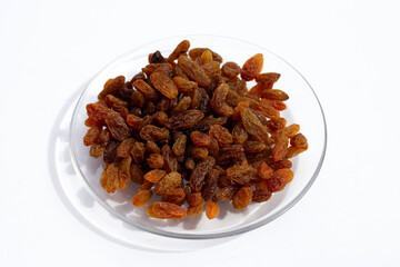 Dried grape raisins in glass plate on white background