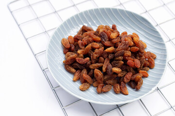 Dried grape raisins in plate on white background