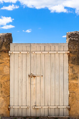 Mediterranean Gateway Background / Shabby white door at an exterior wall under blue sky (copy space)