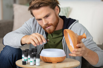 man drips essential oil into an aromatherapy diffuser