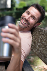 happy man drinking coffee on a wooden bench