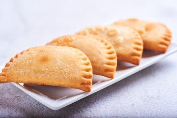 Empanadillas rellenas de atun con tomate y cebolla sobre un fondo blanco.