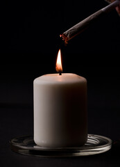 burning candle, with cigar with fire black background. (focus on candle)