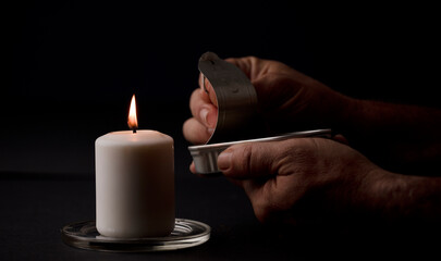concept of energy blackout, lit candle, with can of preserves in man's hands, energy poverty....