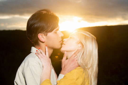 Sensual portrait of young couple in love. Embraces of a loving couple on sunset. Loving couple embracing and kissing.