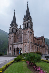 Main facade of the Sanctuary of the Virgin of Covadonga, Asturias, Spain, with its two tall bell towers and its characteristic reddish stone, vertical