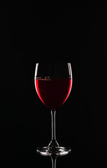 Glass of delicious red wine on black background