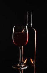 Bottle and glass of red wine on black background