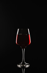 Glass of delicious red wine on black background