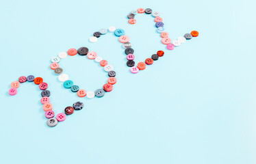 Number 2022 from multi-colored buttons on light blue.